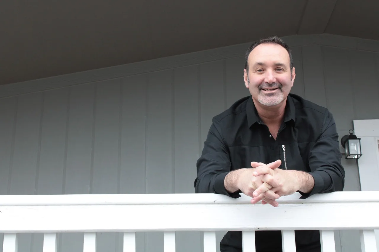 JR, owner of Columbia Gorge Affordable Homes, smiling on the porch of a home